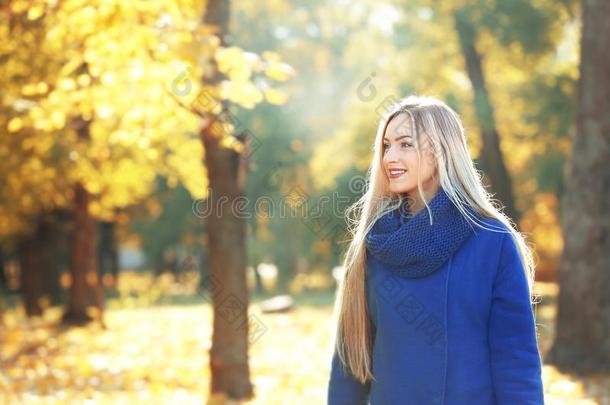 美丽的年幼的女人采用秋公园向一天