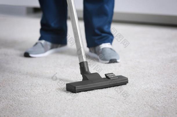木头支架关于男人用真空吸尘器打扫地毯和清洁剂