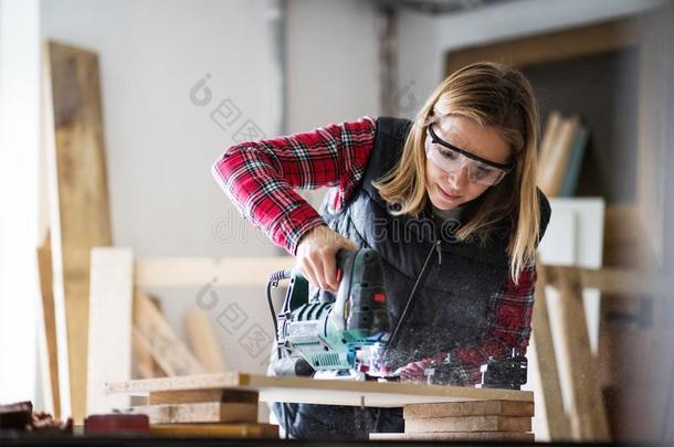 年幼的女人工人采用指已提到的人木工工作间.