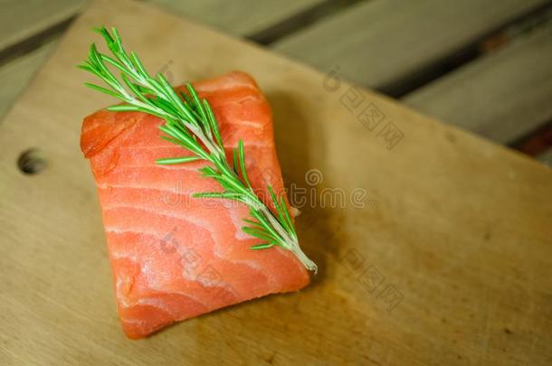 生的鲑鱼肉片和迷迭香向锋利的板