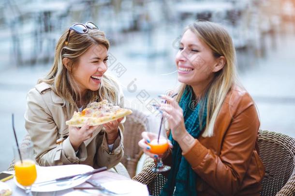 肖像关于两个年幼的女人吃意大利薄饼在<strong>户外</strong>