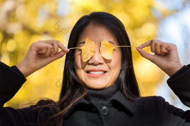 黄色的银杏树树叶采用女人手向眼睛