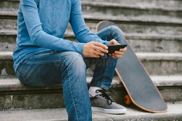 滑板运动员使用智能手机向城市楼梯