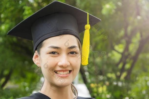 女人学生微笑和感觉幸福的采用<strong>毕业</strong>长袍和盖