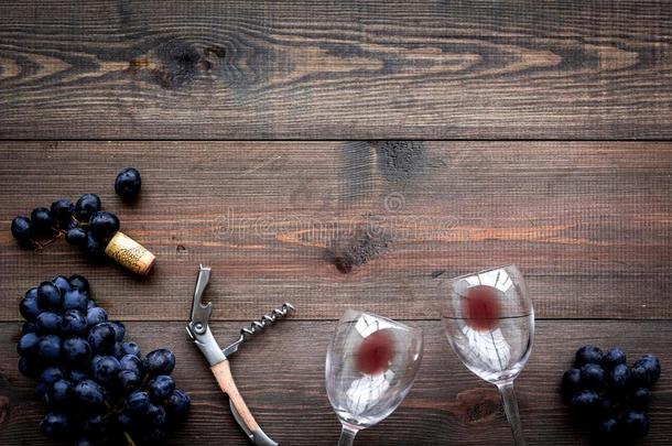 玻璃和葡萄酒沉淀物和葡萄向黑暗的木制的背景顶