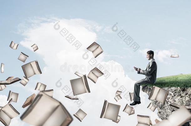男人使用智能手机和许多书飞行的采用天空