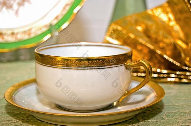古老的茶杯向茶杯托和认为金边