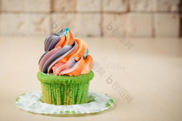 富有色彩的彩虹纸杯蛋糕向表向砖墙背景.