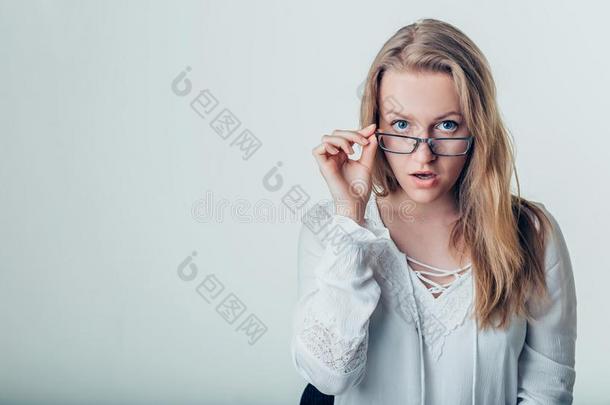 惊奇的年幼的女人采用眼镜越过灰色背景