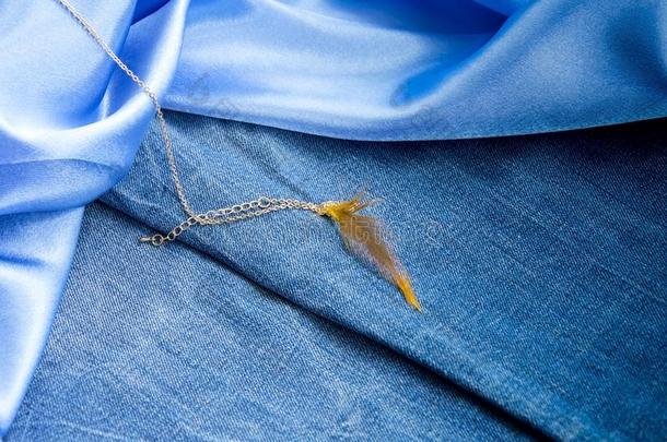 密集的蓝色斜纹粗棉布织物,光滑的天-蓝色丝和金链子机智