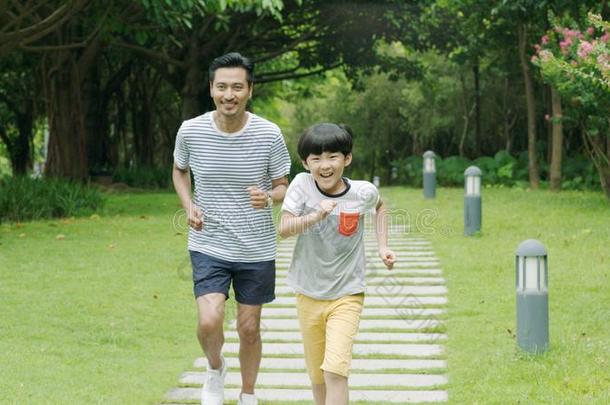 亚洲人父亲&儿子微笑的&跑步采用公园采用夏