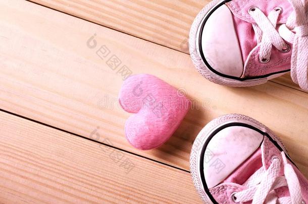 粉红色的女孩旅游鞋和粉红色的心向一木制的地面