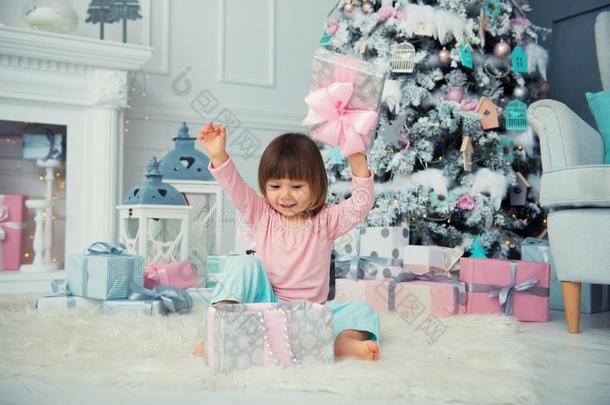小的婴儿女孩开新的年赠品在近处圣诞节树