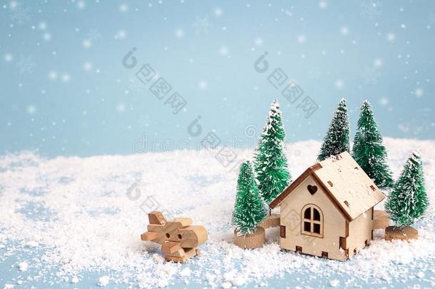 冬小型的房屋和冷杉树和飞机向蓝色后面
