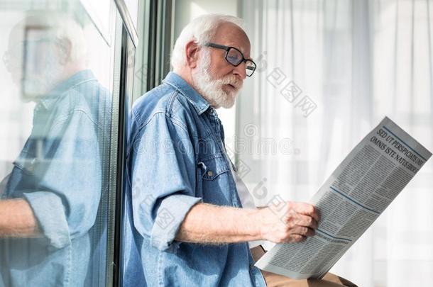 聪明的老年的男人佃户租种的土地日报在期间有根基的向窗沿