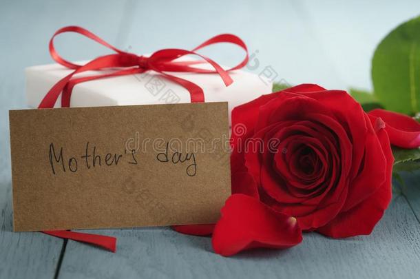 红色的玫瑰向蓝色木材表和赠品和母亲一天纸卡片