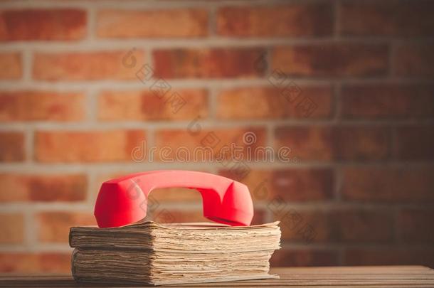 红色的电话听筒越过老的书向木制的表