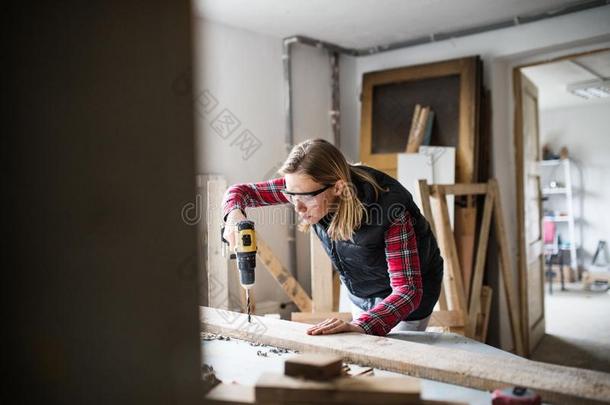 年幼的女人工人采用指已提到的人木工工作间.