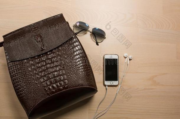 平的放置关于棕色的皮背包,耳机,智能手机和