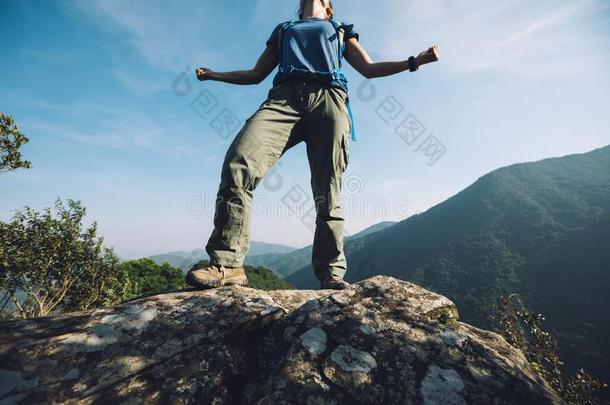 女人背着背包徒步旅行的人起立向悬崖边