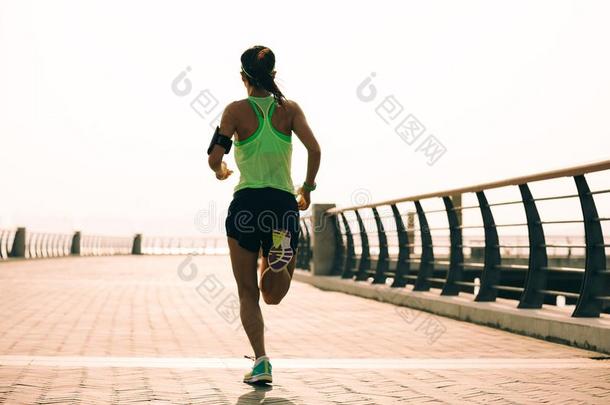 像运动家的女人赛跑者跑步在日出海滨