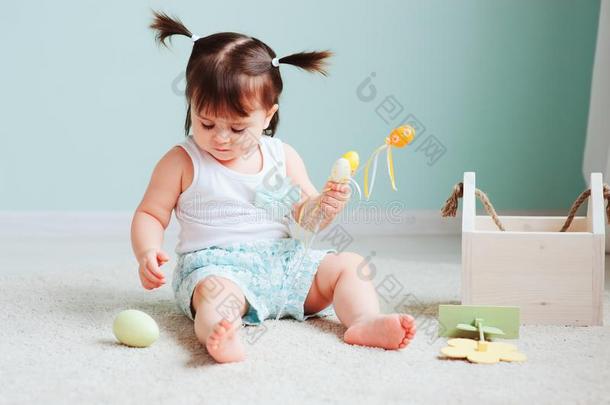 室内的肖像关于漂亮的幸福的婴儿女孩演奏和复活节装饰