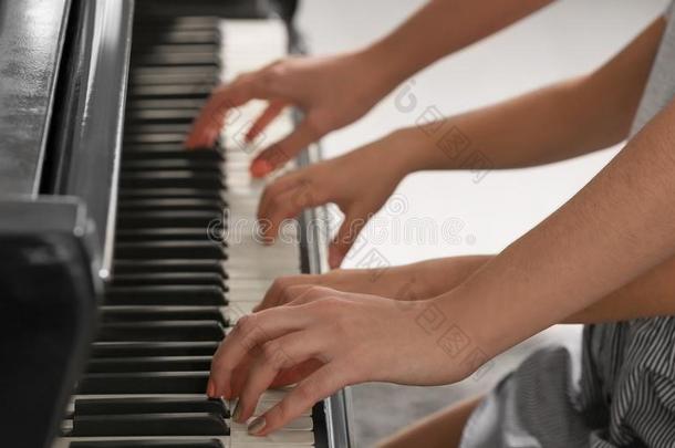 小的女孩演奏钢琴和教师在室内