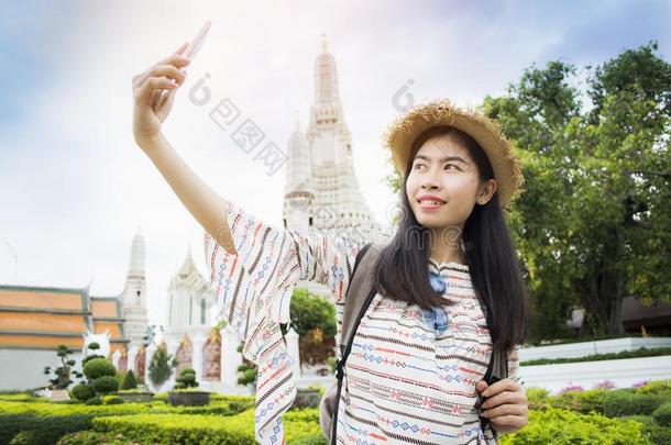 亚洲人女人背着背包徒步旅行的人自拍照在的时候旅行泰国或高棉的佛教寺或僧院阿伦庙