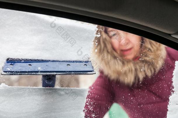 女人清洁雪从汽车窗
