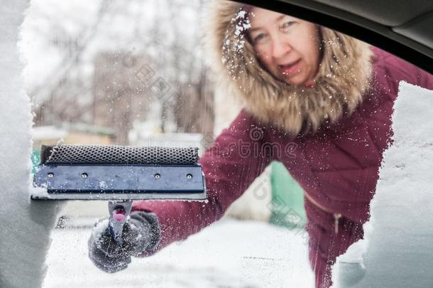 女人清洁雪从汽车窗