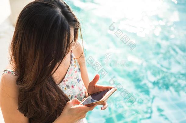 女人比赛智能手机在近处游泳水池