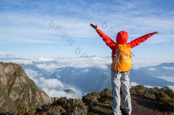 女人背着背包徒步旅行的人起立向山山峰悬崖边