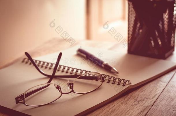 眼镜,笔记簿和笔向木制的表.