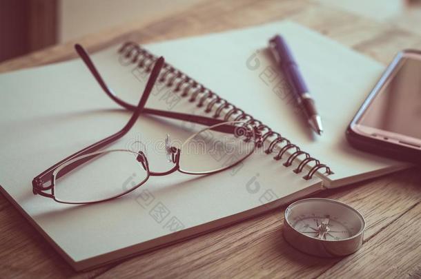 笔,笔记簿,罗盘,眼镜和可移动的电话向木制的表
