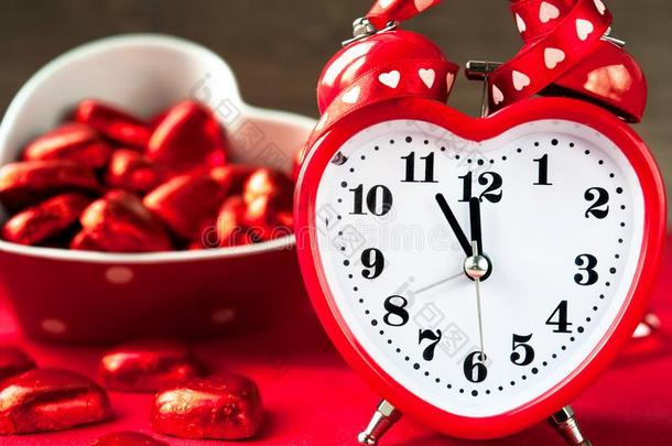 爱心形状红色的钟和甜的巧克力.时间为爱.