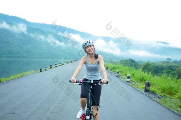 年幼的女人骑马她自行车向指已提到的人湖边