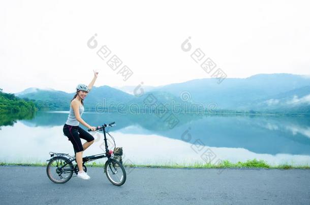 欢乐的年幼的女士骑马指已提到的人自行车向指已提到的人湖边