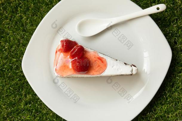 草莓蛋糕和盘子和勺向人造的绿色的草