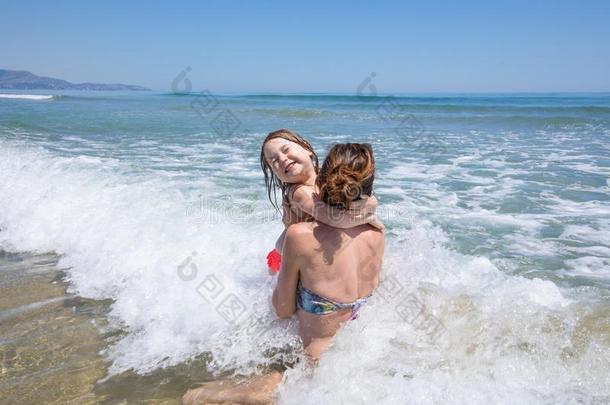 母亲和小孩用于跳跃的波采用西班牙的海滩