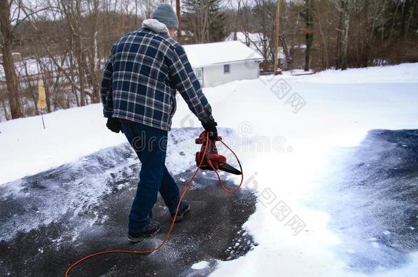 男人使用叶子吹风机向清楚的雪从马路