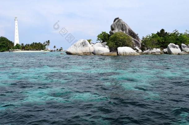 白色的灯塔在的后面美丽的珊瑚岩石和绿色的灌木和
