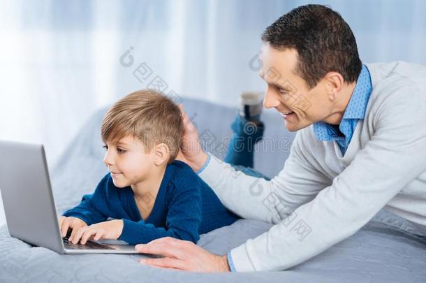 爱的父亲轻拍上<strong>端</strong>关于他的儿子使用便携式<strong>电脑</strong>