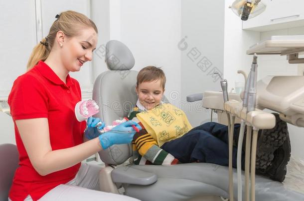 指已提到的人牙科医生展映指已提到的人小的男孩怎样向干净的指已提到的人牙和一