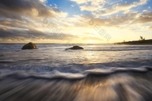 日落向海滩波和岩石
