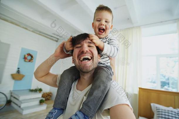 幸福的父亲运送的他的微笑的儿子向颈和制造自拍照