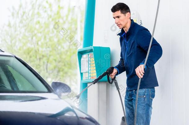 专注的工人洗涤汽车和高的-压软管