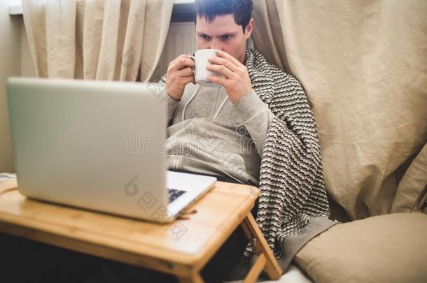 年幼的男人产卵数采用坏的和便携式电脑和杯子关于茶水.