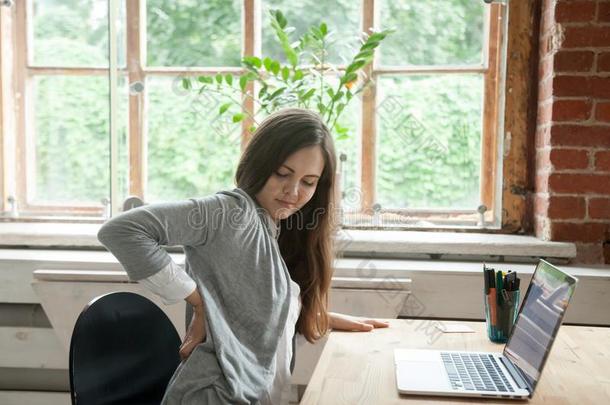 年幼的女人摸索不舒服的一次采用办公室椅子,马萨吉