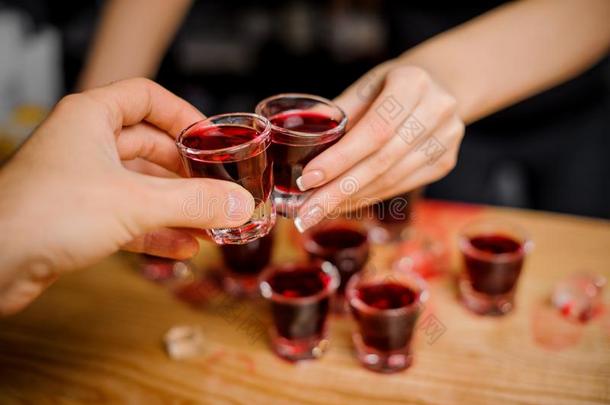 酒吧女招待发出叮当声眼镜和一红色的-colo红色的一lcohol和一客人