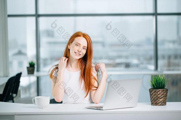 美丽的红发的人女孩工厂在便携式电脑和有样子的在照相机